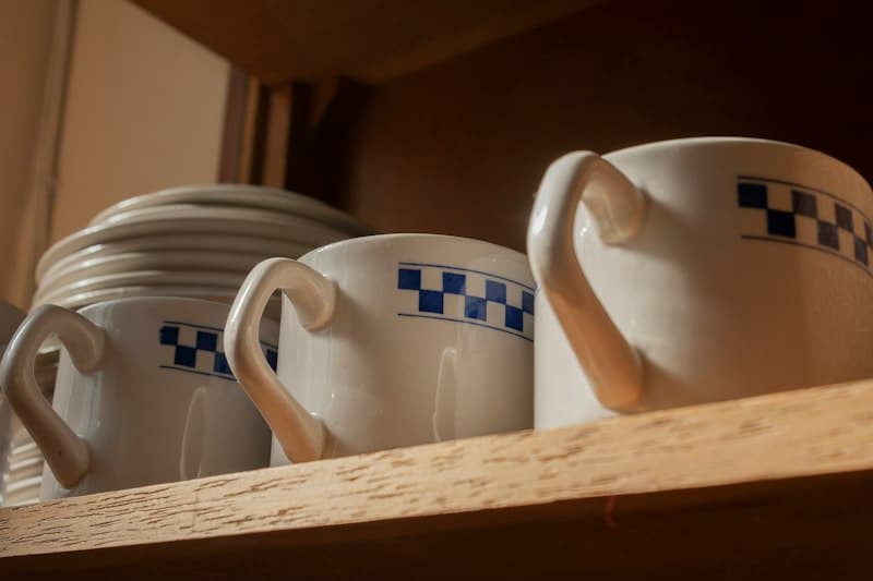 A shelf filled with white and blue coffee cups in a tidy display